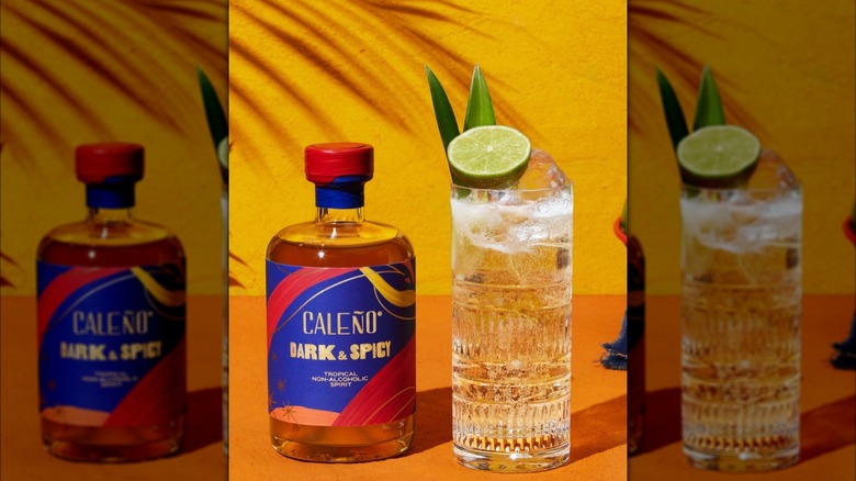 Bottle of Caleño dark and spicy next to cocktail in glass on yellow background