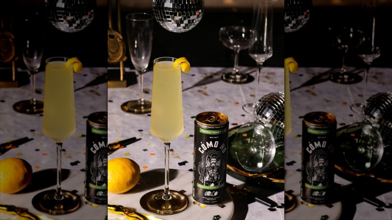 Can of prickly pear Cómo No next to champagne flute with yellow liquid on party table