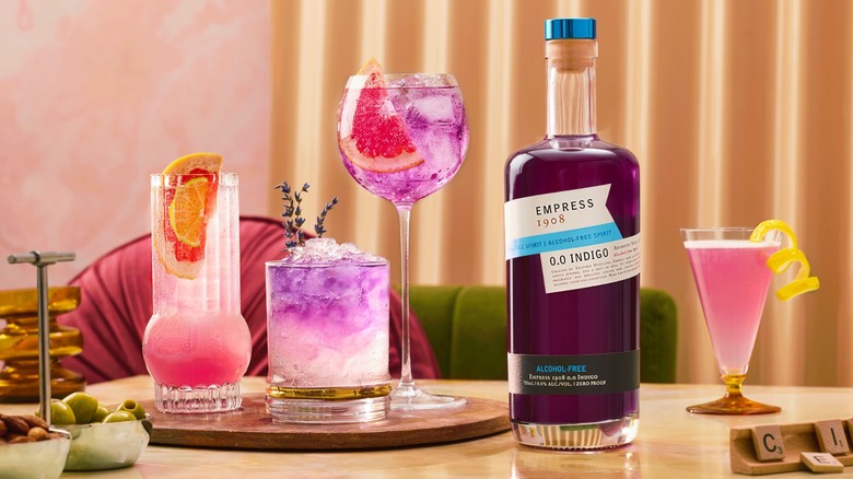 Bottle of Empress 1908 Gin 0.0 Indigo on table among various cocktails