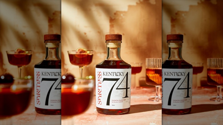 Bottle of Spiritless Kentucky 74 surrounded by drink glasses, beige background