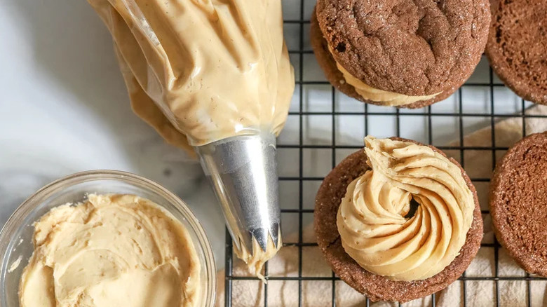 Easy Espresso Frosting in piping bag next to frosted cookies on baking tray