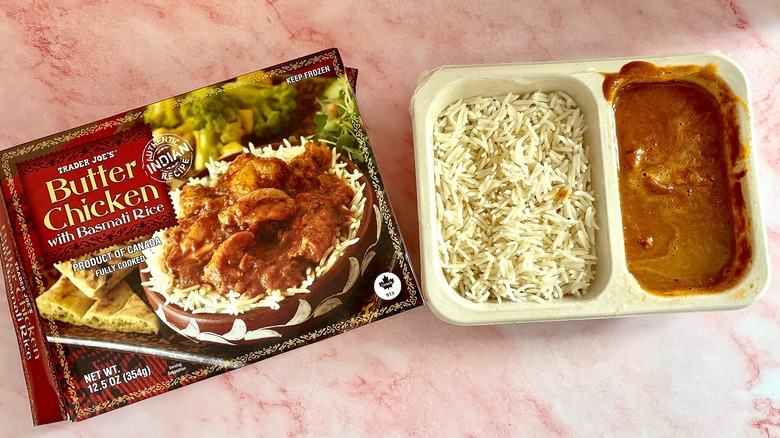 Trader Joe's cooked butter chicken and rice next to box on pink marble surface
