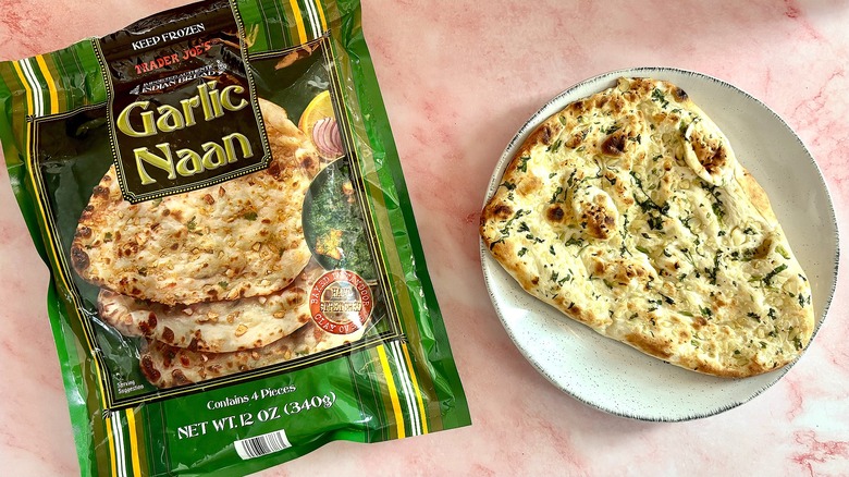 Garlic naan on plate next to package on pink marble surface
