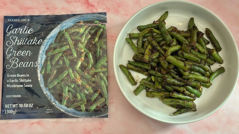 Trader Joe's garlic shiitake green beans in white bowl next to bag on pink marble surface