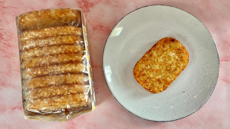 Trader Joe's hashbrown on white plate next to box of hashbrowns on pink marble surface