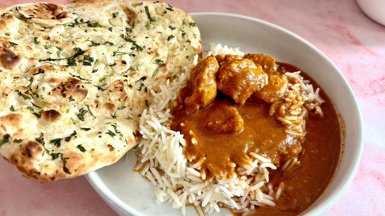 White bowl holding Trader Joe's butter chicken and rice along with garlic naan