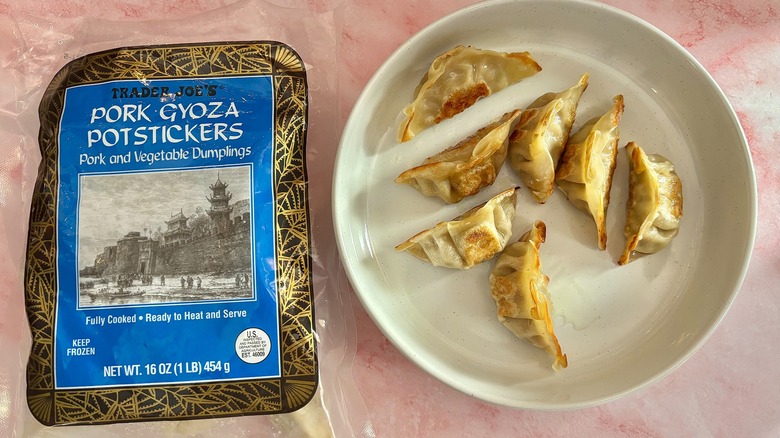 Trader Joe's Pork gyoza potstickers in white bowl next to bag on pink marble surface