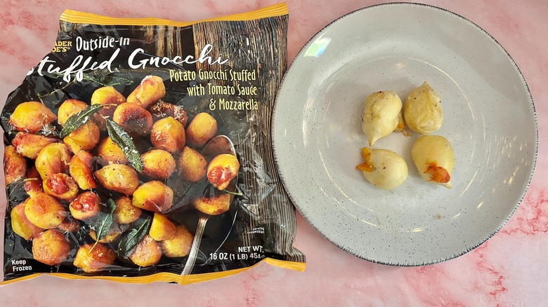 Trader Joe's stuffed gnocchi on white plate next to bag of gnocchi on pink marble surface