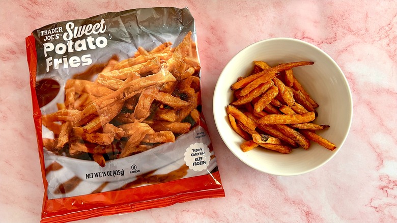 Sweet potato fries in bowl next to package on pink marble surface