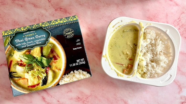 Thai green curry in container next to package on pink marble surface
