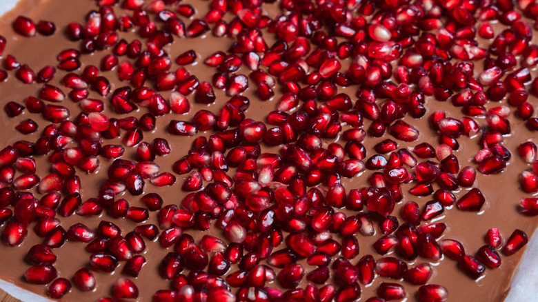 Pomegranate seeds submerging in melted chocolate