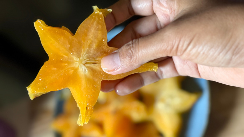 Person holding sliced yellow starfruit