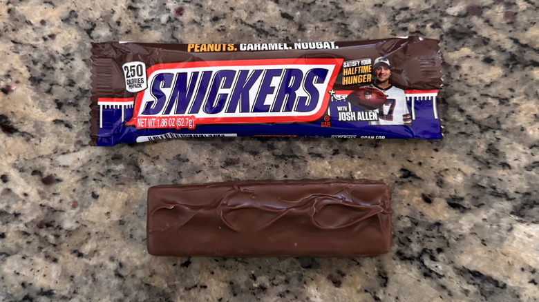 snickers bar on counter beside wrapper