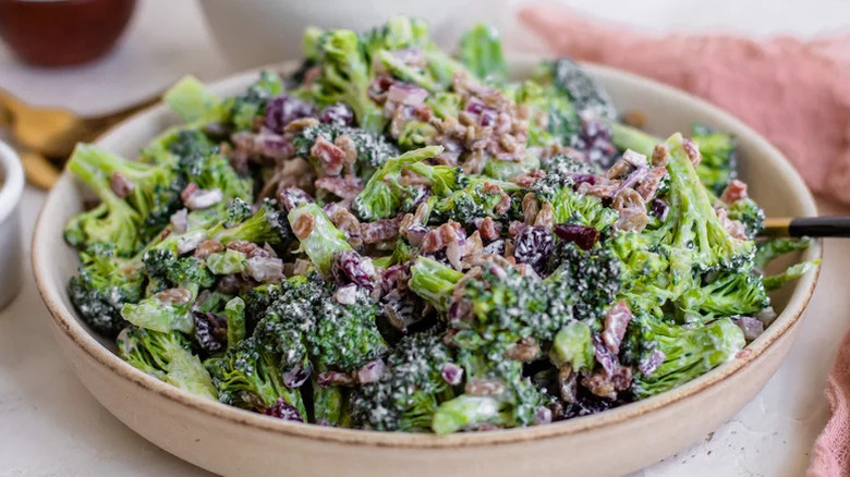 Bowl of broccoli salad topped with nuts and raisins