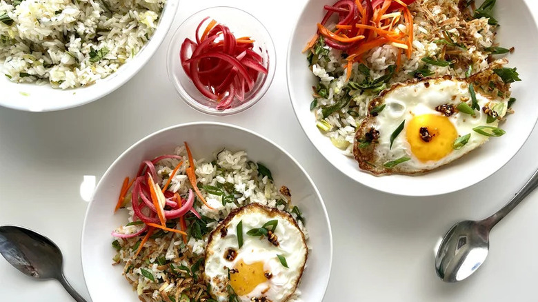 Two dishes plated with coconut rice and fried eggs