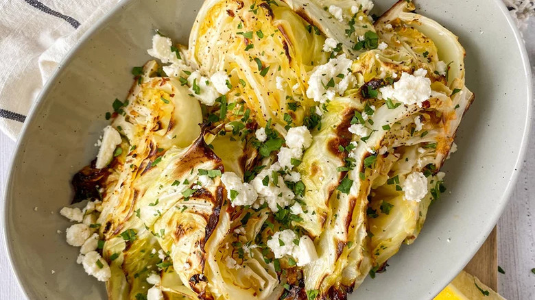 Bowl of roasted cauliflower wedges topped with parsley and feta cheese