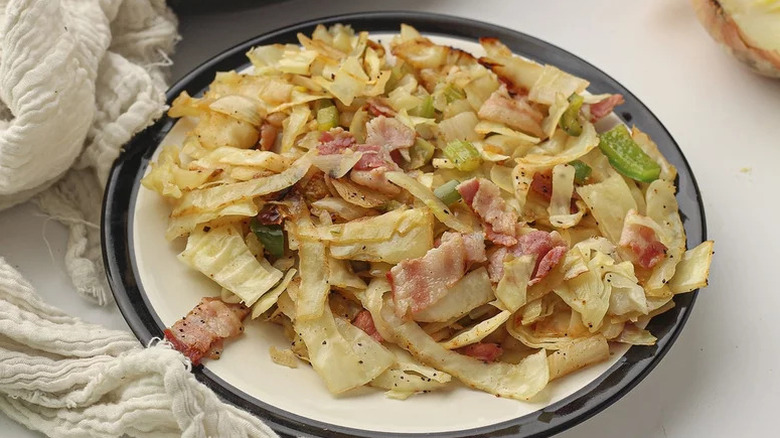 Plate with southern fried cabbage topped with bacon and green pepper