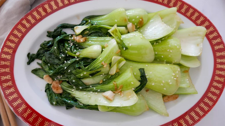 Red and white plate filled with stir-fried bok choy