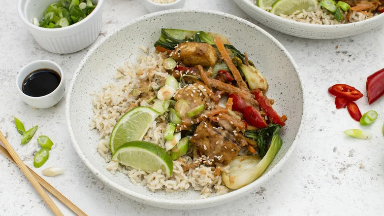 Tofu and Bok Choy Stir-Fry in a dish with rice and peanut sauce surrounded by ingredients