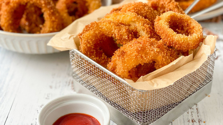 Crispy fried onion rings in parchment-lined basket