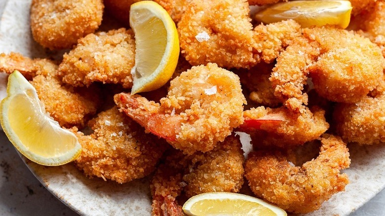 Crispy panko fried shrimp on plate with lemon wedges