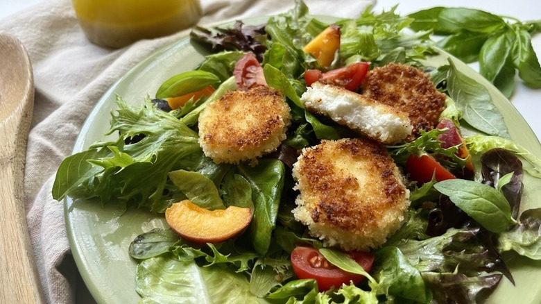 Plate of salad topped with breaded fried goat cheese