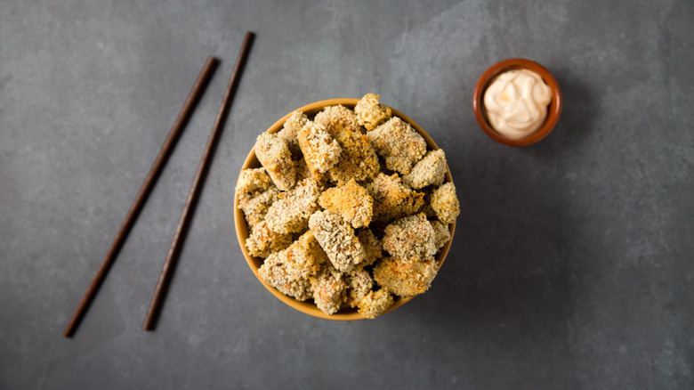 Bowl of crispy popcorn tofu next to chopsticks and pot of mayo