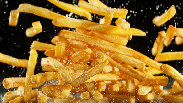 Fast food French fries flying in air with salt
