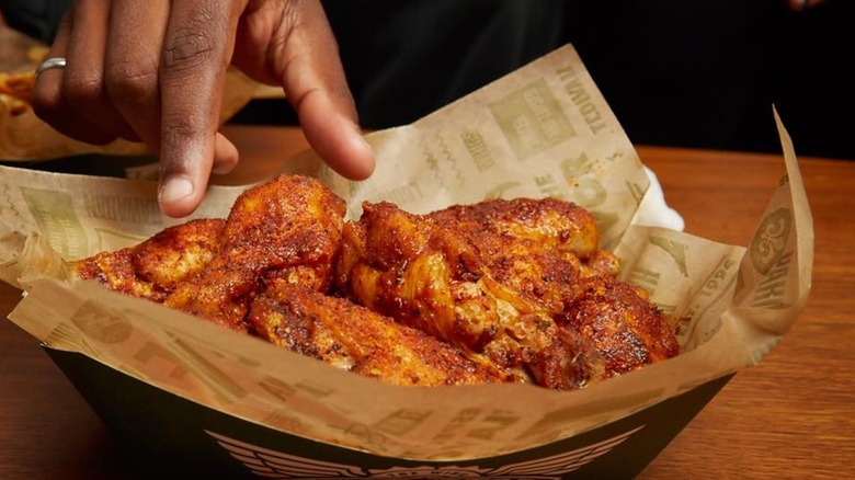 Hand reaching for Wingstop wings
