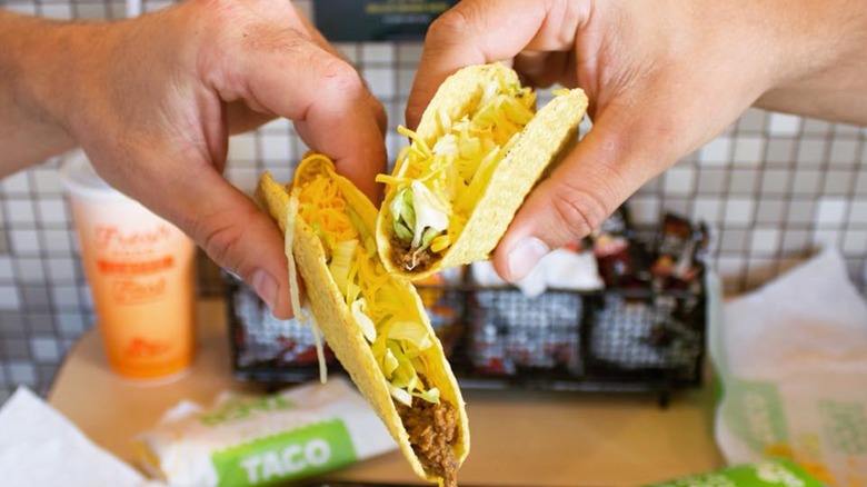Two hands holding snack tacos at Del Taco