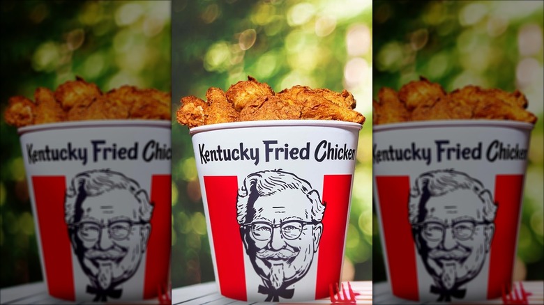 KFC bucket of fried chicken outdoors on a picnic table with a red fork