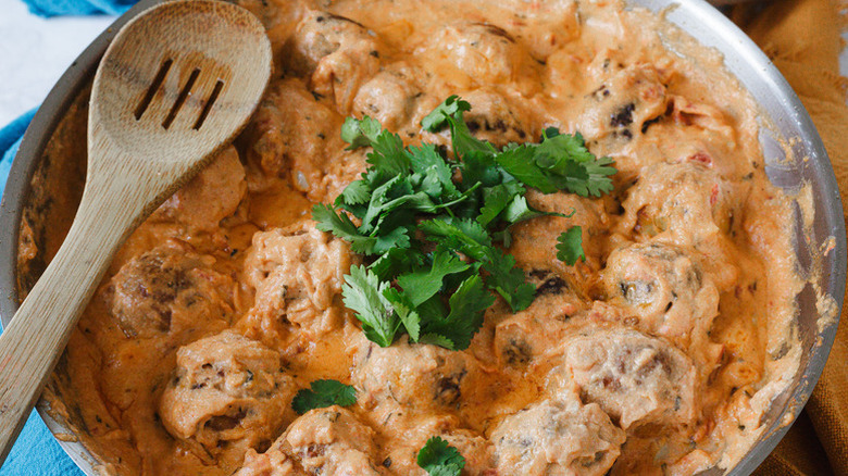 Paneer dumplings in skillet with creamy sauce, topped with cilantro