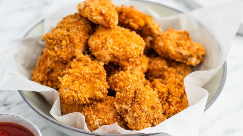 Pile of chicken nuggets in parchment-lined bowl