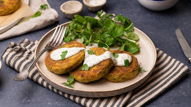 Crab cakes on plate with creamy sauce and side salad