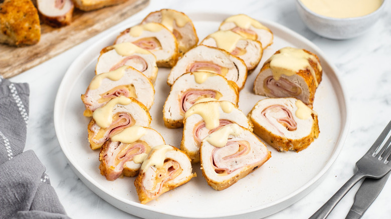 Sliced chicken cordon bleu on plate, drizzled with creamy sauce