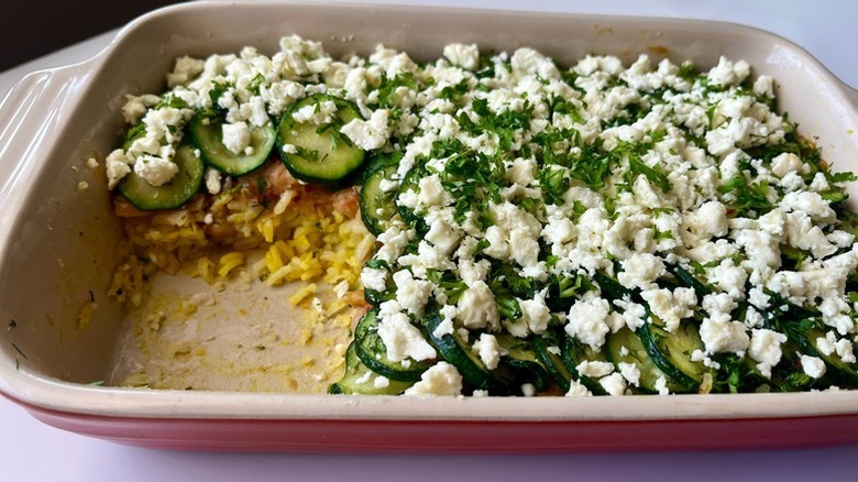 Zucchini and rice casserole in baking dish, topped with crumbled feta cheese