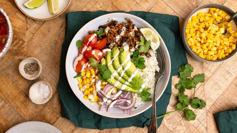 Ground beef rice bowl with avocado, red onion, tomatoes, and corn