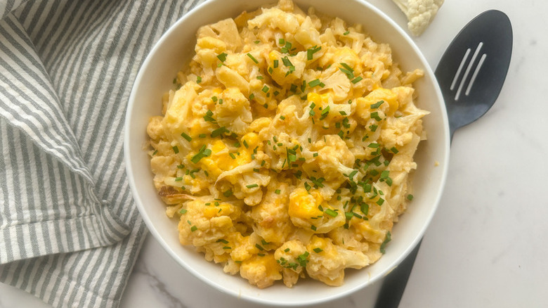 Bowl of cauliflower mac and cheese, garnished with chopped chives