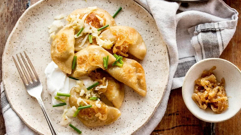 Homemade Pierogi on beige plate with sour cream
