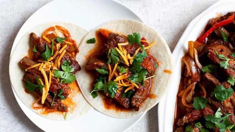 Crockpot Steak Fajitas on tortillas on white plate