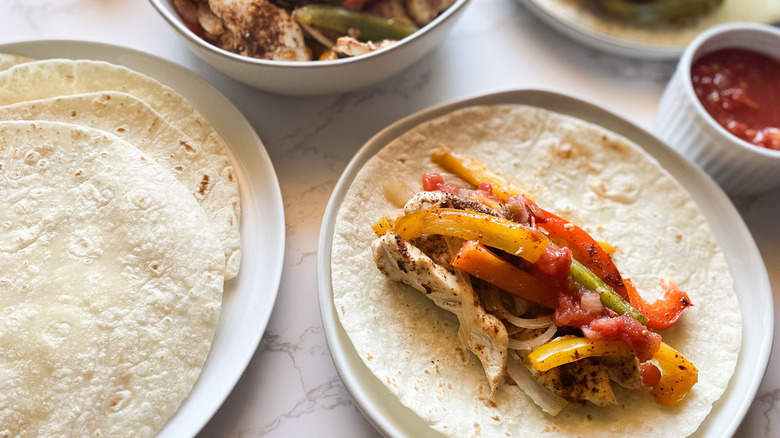 Homemade Chicken Fajitas on white plate with tortillas