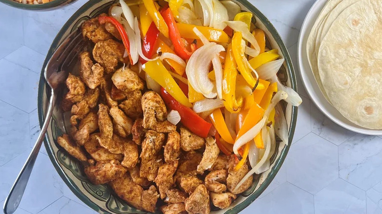 Sheet Pan Chicken Fajitas with Spicy Avocado Crema arranged in bowl