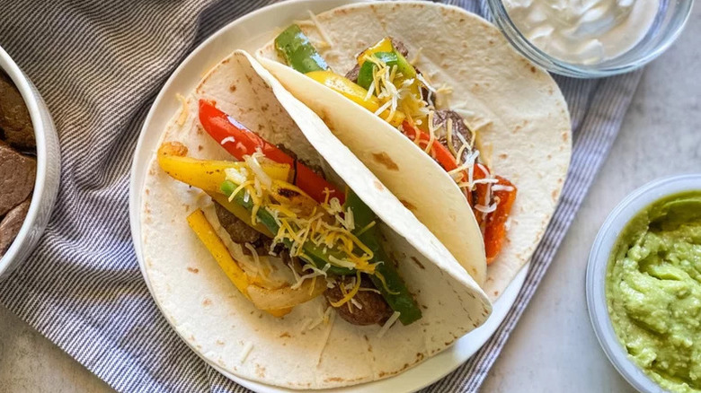 Venison Fajitas in tortillas on white plate with kitchen towel