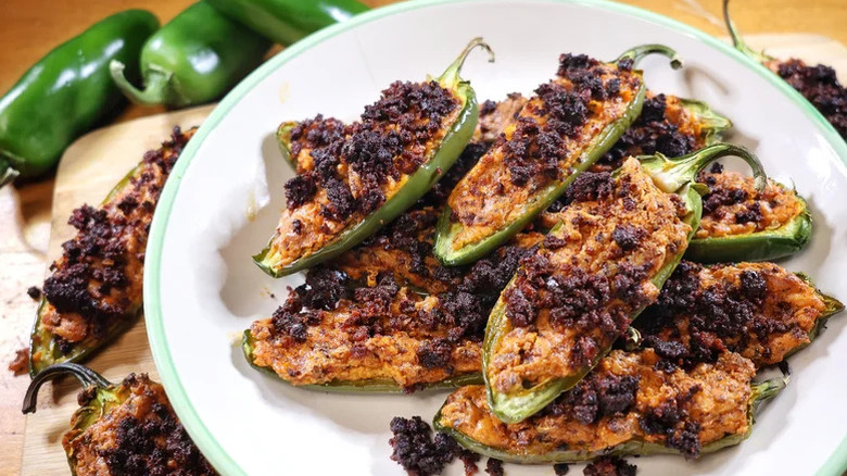 plate of stacked chorizo jalapeño poppers with more poppers and peppers around it