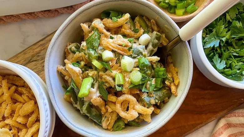 top view of a green bean casserole in bowl next to small bowls filled with garnishes