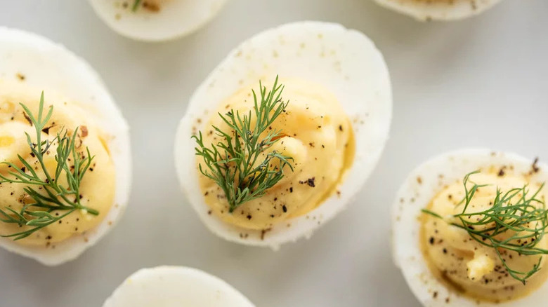 closeup deviled eggs with dill sprinkled with pepper