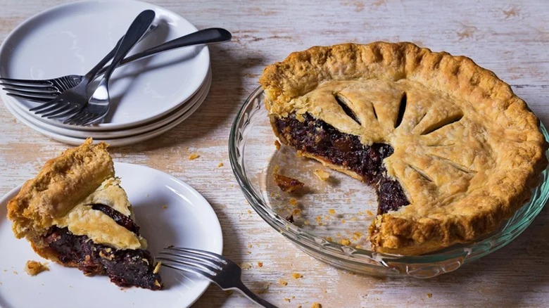 Mincemeat pie with slice on plate and more plates with forks