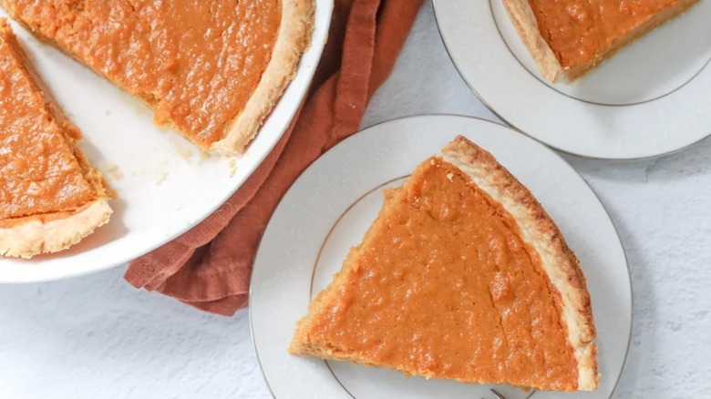 Slice of maple-bourbon sweet potato pie on plate beside pie