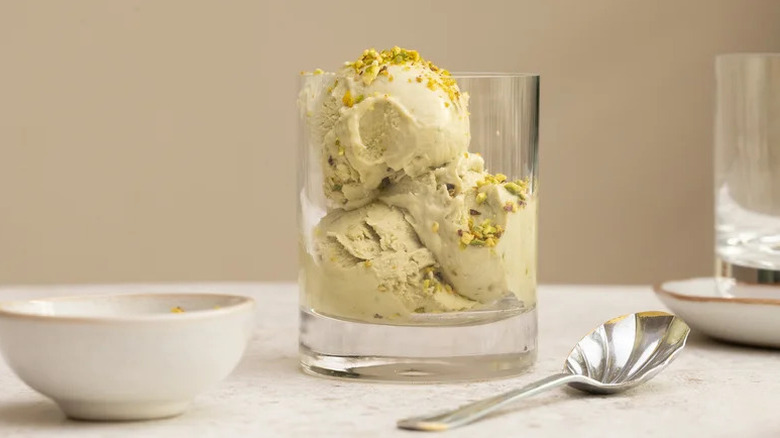 Three scoops of no-churn pistachio ice cream in glass jar with silver spoon