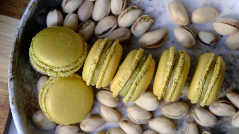 Pistachio macarons on plate with shelled pistachios